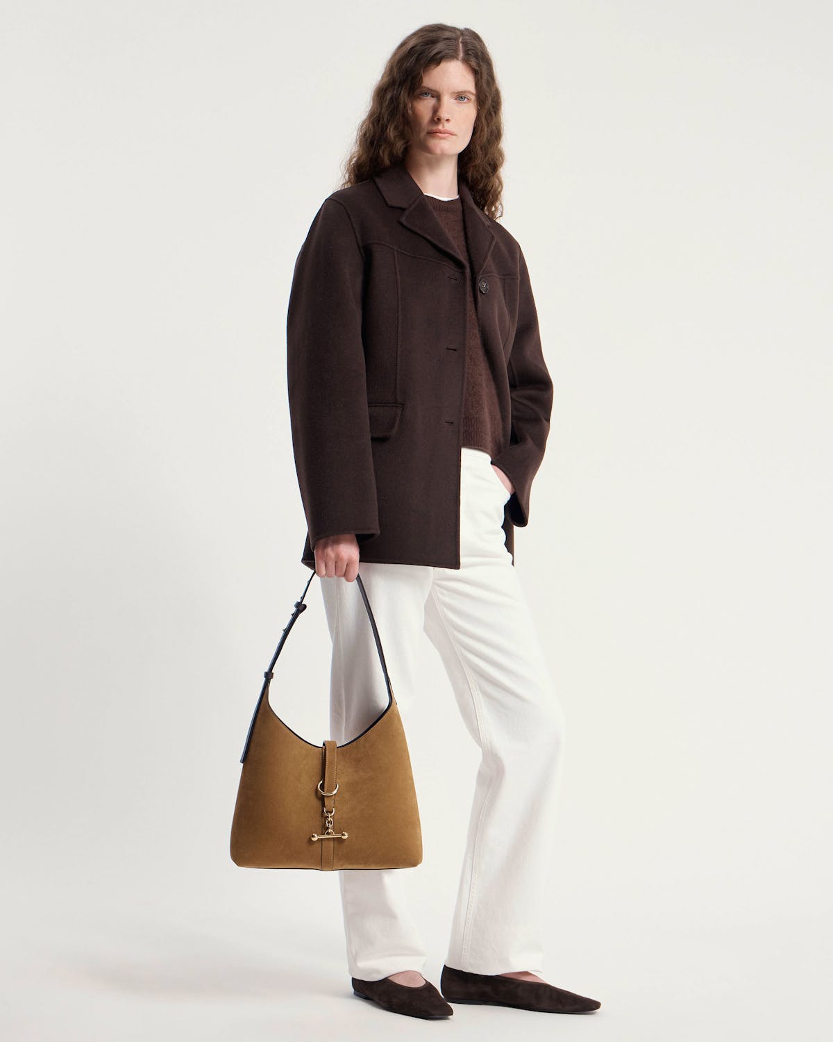Model holding toffee suede hobo bag with espresso strap and gold hardware.