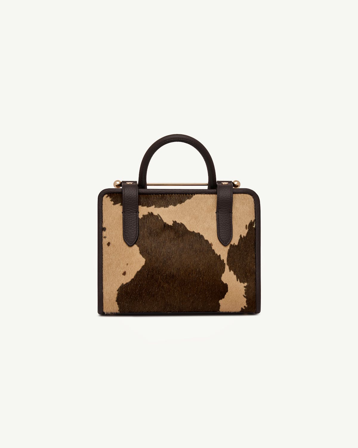 Mini tote with sand and espresso spot print and dark brown leather handles.