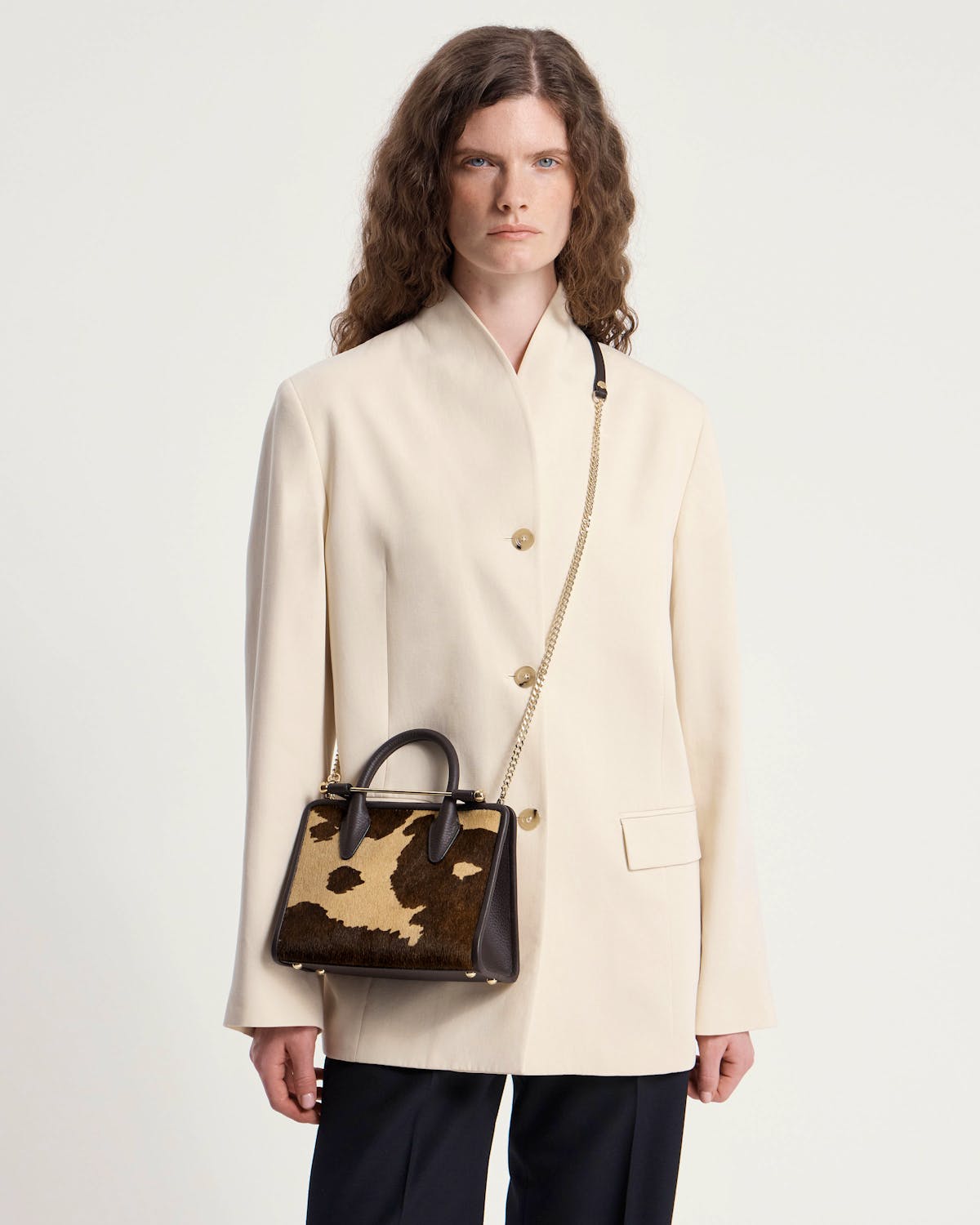 Model wearing cream blazer with mini tote in sand and espresso spot print.