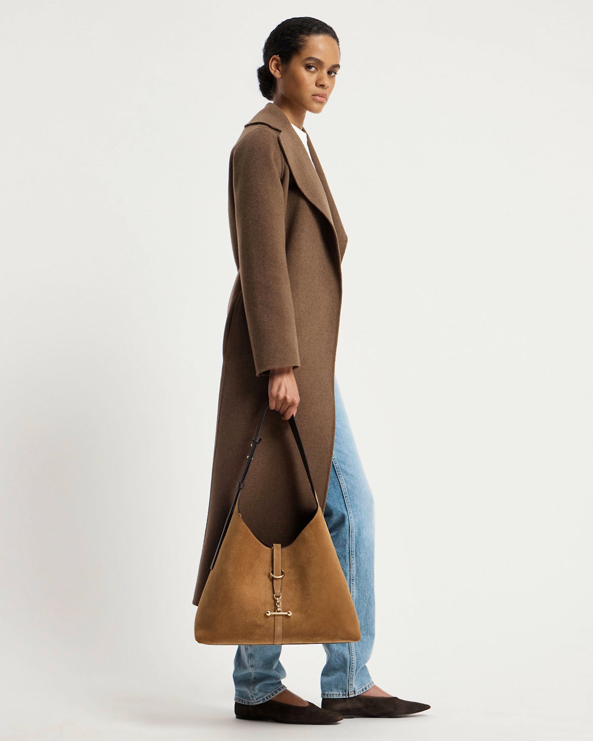 Model wearing a brown coat holding a toffee suede hobo bag with espresso strap.