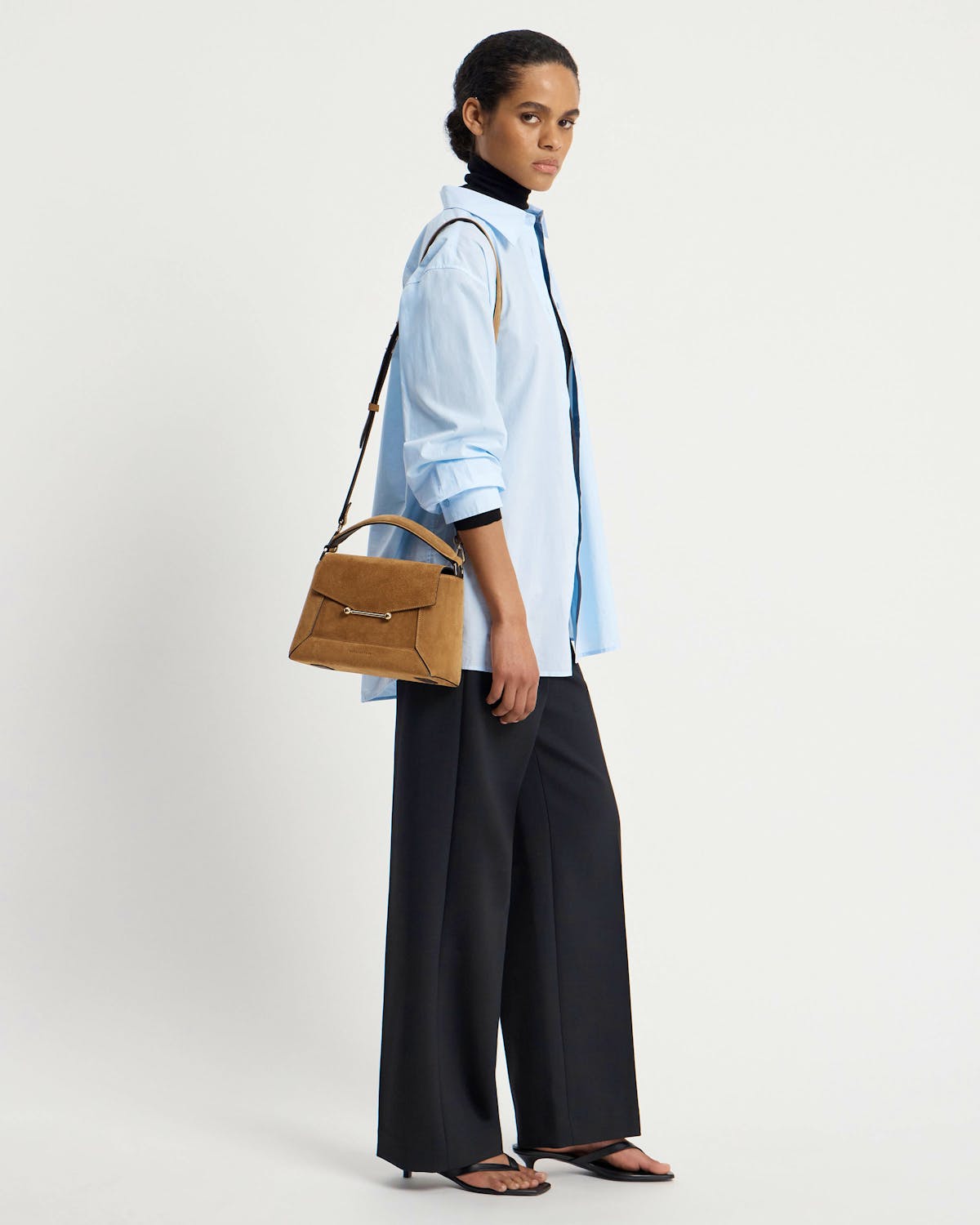 Model in light blue shirt carrying toffee suede Mosaic bag with shoulder strap.