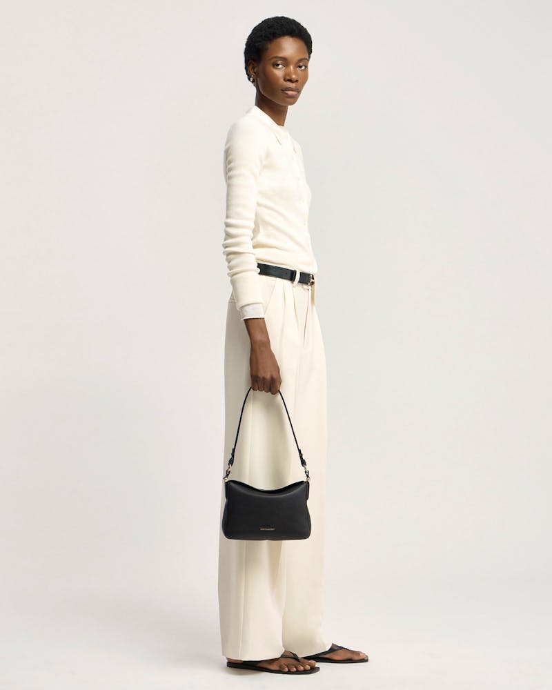 Model holding black Strathberry Sway shoulder bag at her side